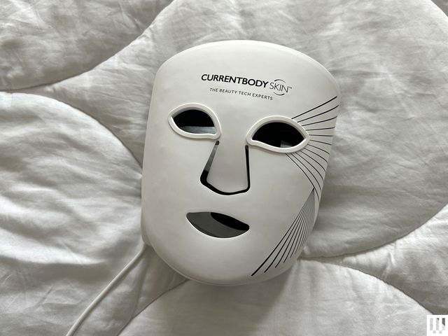 Current Body LED Face Mask Series 2, a white facial mask laying on a white blanket