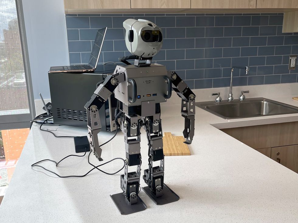 A small humanoid robot standing on a kitchen counter.