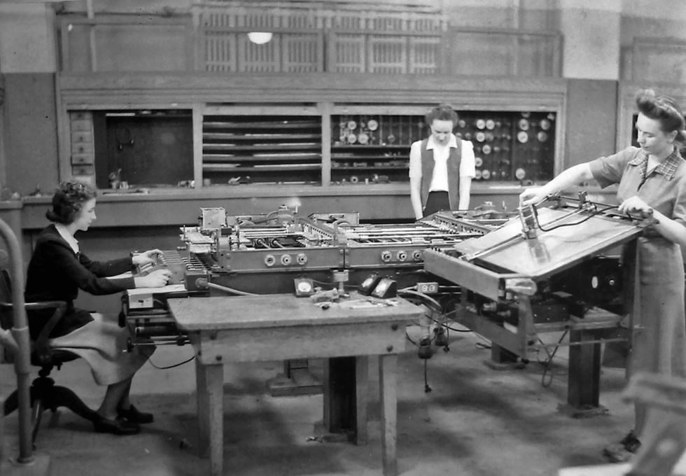Black and white 1940s image of three women operating a differential analyser in a basement.