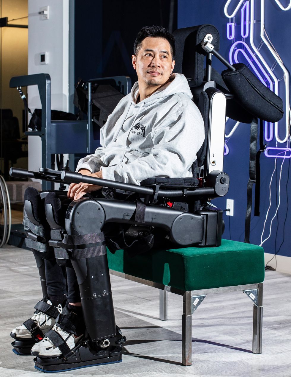 Person seated wearing a full lower-body robotic exoskeleton for mobility assistance