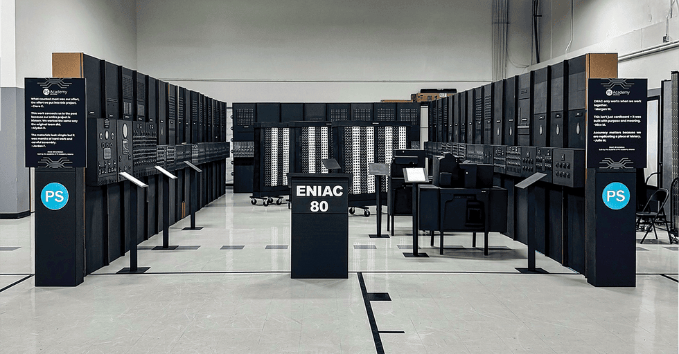 recreation of a large machine arranged in a U shape. A podium in the middle reads u201cENIAC 80u201d