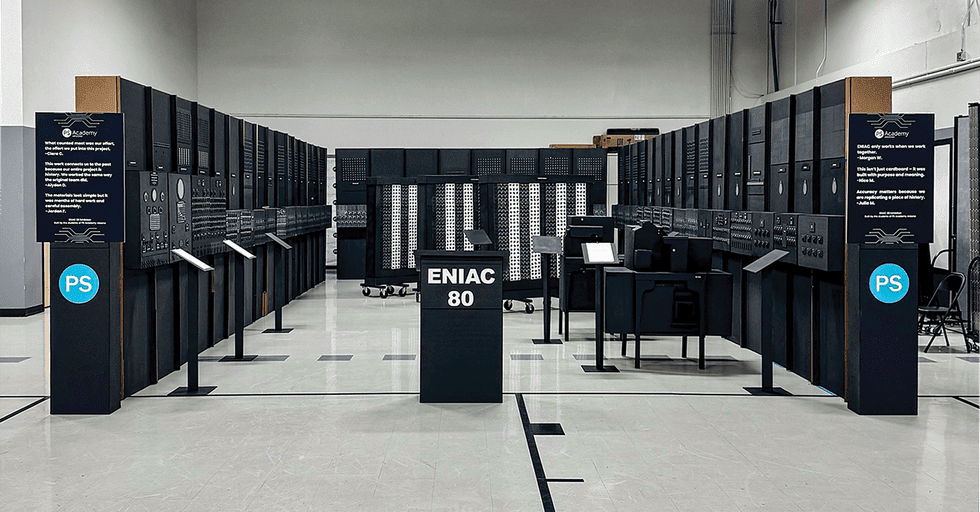 recreation of a large machine arranged in a U shape. A podium in the middle reads u201cENIAC 80u201d