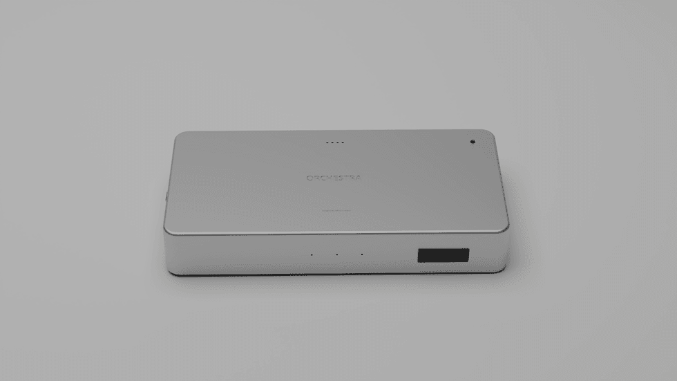 Sleek silver rectangular electronic device labeled u201cORCHESTRAu201d on a light gray background.