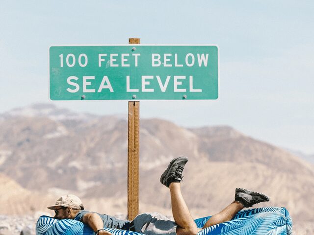 Person laying on a Chillbo Shwaggins inflatable couch in a dried up desert