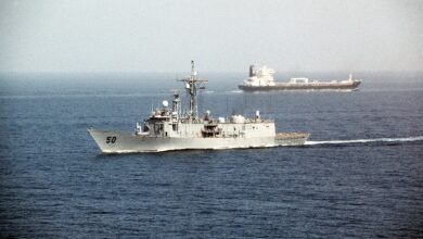 A tanker and a United States naval vessel passing through the Strait of Hormuz