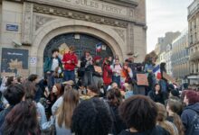 Students gather outside Lycée Jules Ferry in Paris with placards during a school protest.